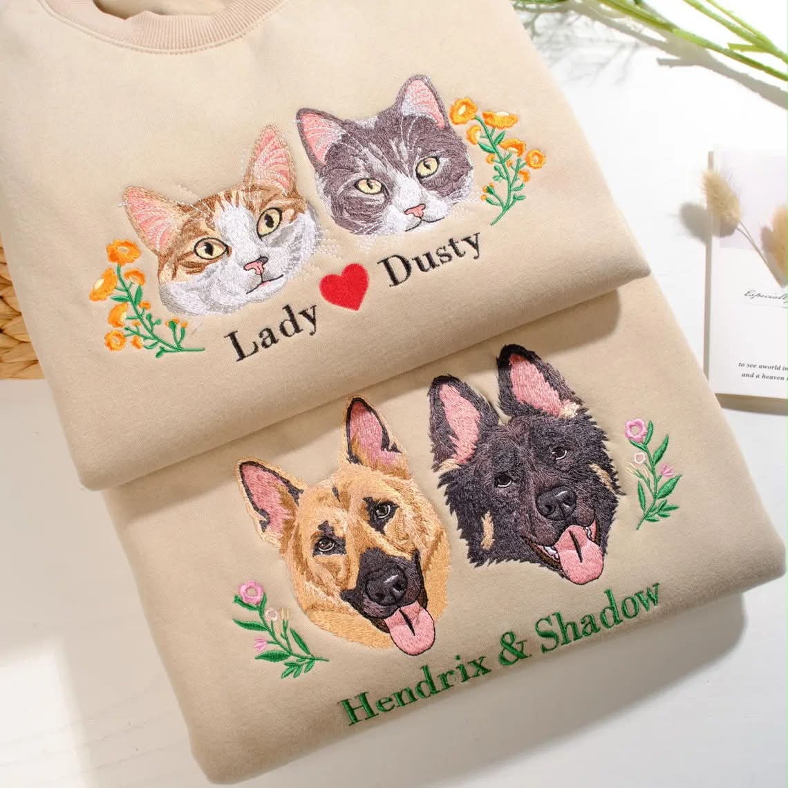 Real embroidery samples of two cats and two dogs on folded cream cotton shirts